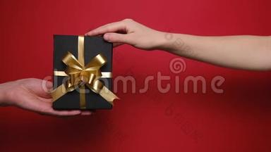 年轻夫妇双手拿着红色背景上的手工礼盒。 圣诞节，情人节和生日概念。